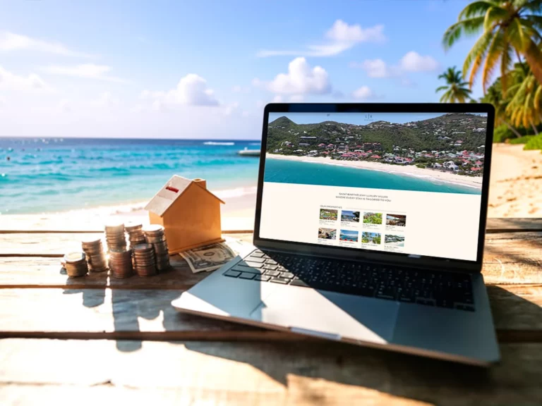 Alt text: “Laptop showing the thelrgroup.com villa website developed by Sevencope on a tropical beach table beside coins, cash, and a small house model.